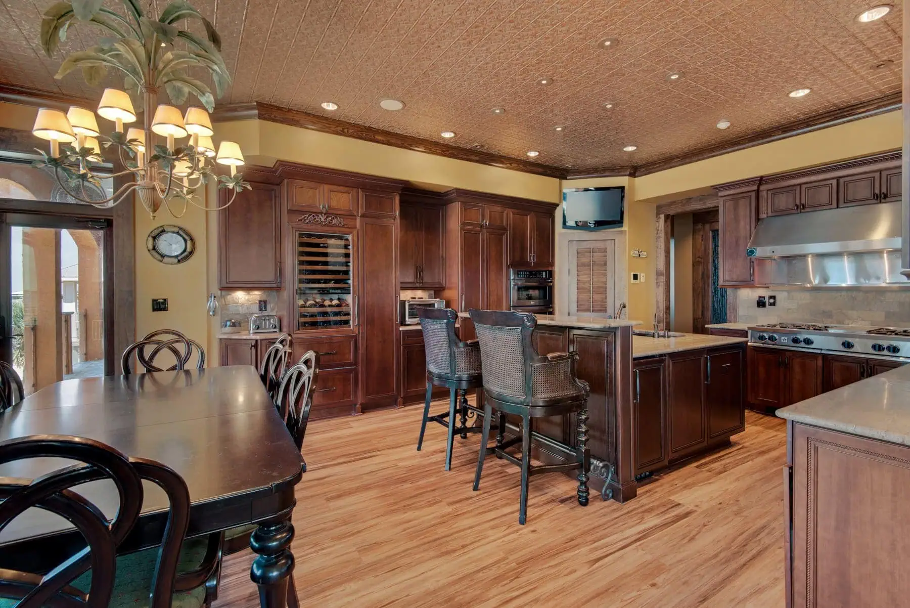 Mediterranean estate kitchen with custom cabinetry, wine refrigerator, and island seating in Pensacola Beach.