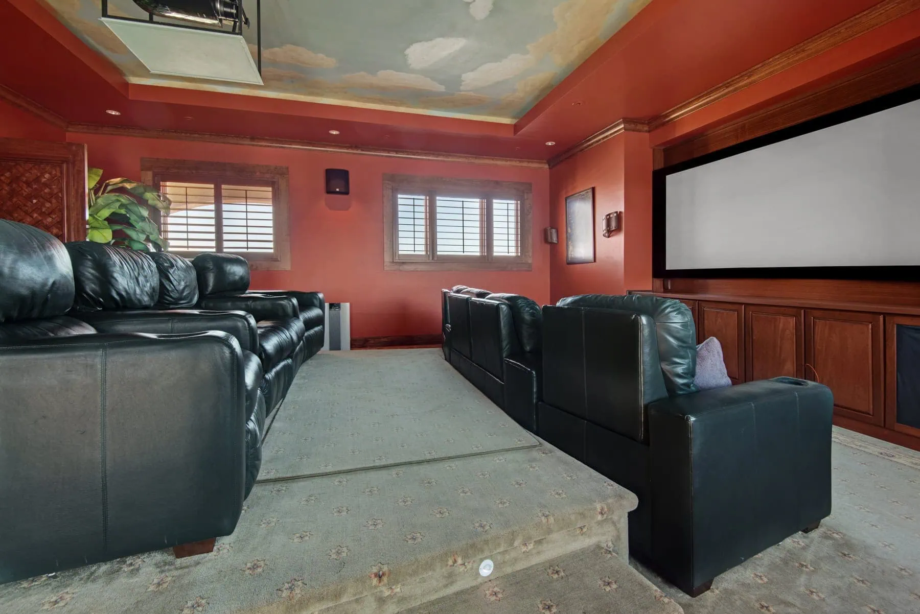 Mediterranean estate home theater with black leather seating and large screen.