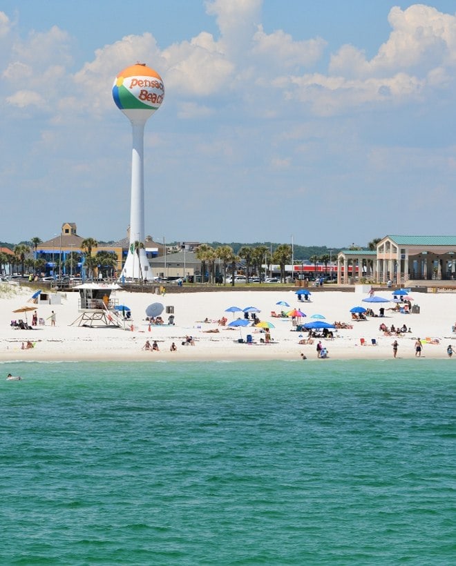 Pensacola Beach water tower overlooking white sand beach and Gulf Coast shoreline.