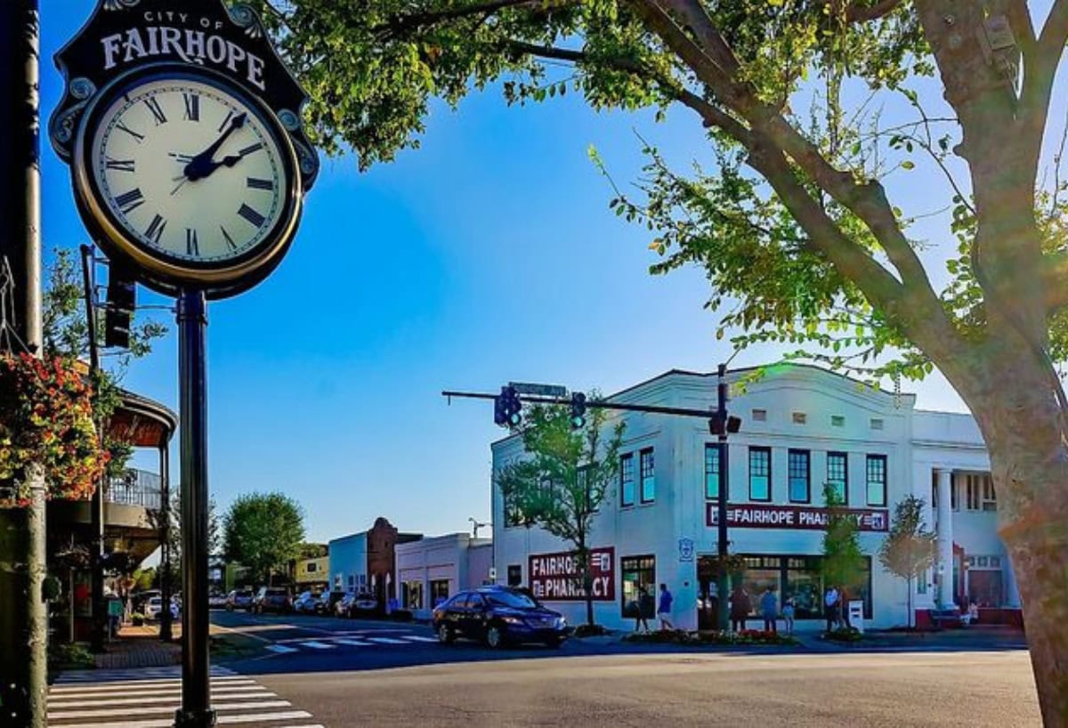 Fairhope city clock and downtown streetscape with historic buildings and pharmacy.