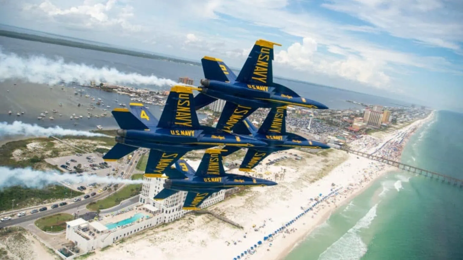 US Navy Blue Angels aerial demonstration over Gulf Coast beach and waterfront property.